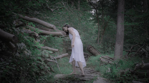 Woman standing on field in forest