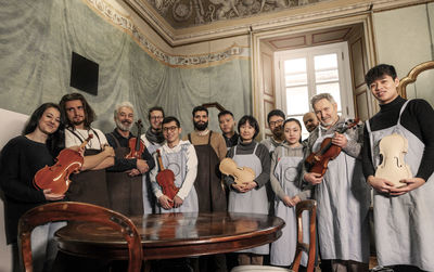 Group of people teachers and students violin maker while posing in a historic room