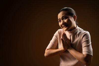 Portrait of smiling girl standing against black background