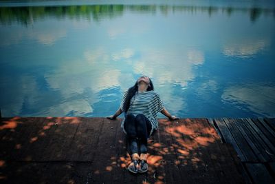 Woman sitting on pier by lake