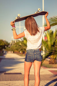 Rear view of woman with umbrella standing against sky