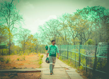 Full length of man walking on footpath against sky