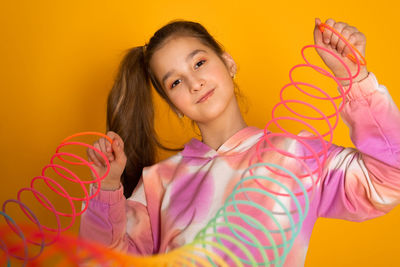 Teen girl play rainbow slinky toy on color background