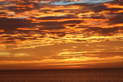 Scenic view of sea against dramatic sky during sunset