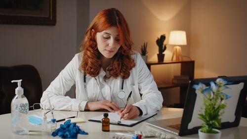 Young italian doctor writes prescription on pen and paper for medicines