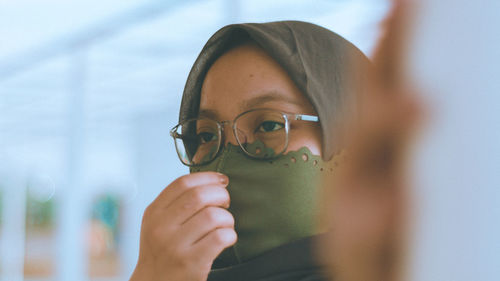 Close-up portrait of young woman holding eyeglasses