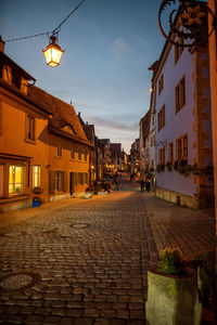 Street amidst buildings against sky at sunset