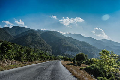 Road leading towards majestic mountains against sky