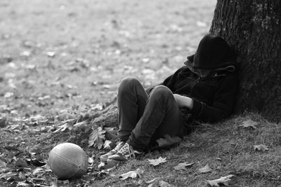 Boy napping by rugby ball in park