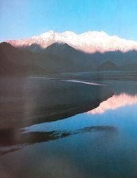 Scenic view of lake by mountains against sky