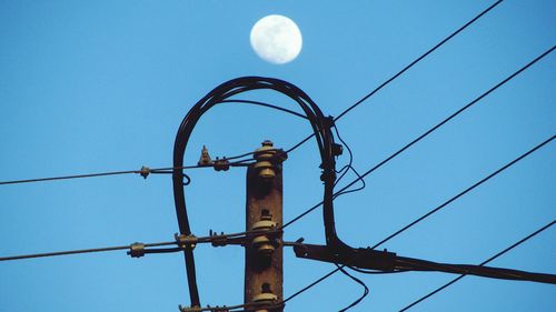 Low angle view of power lines against blue sky