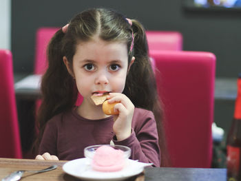 Portrait of a beautiful one child girl eating ice cream in a cafe.