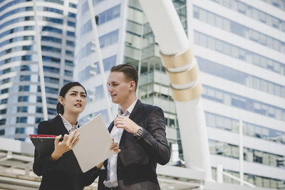 Low angle view of business people discussing while standing against building