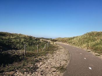 Road amidst landscape against clear blue sky