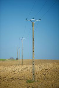 Electricity pylon on field against clear sky