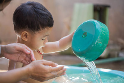 Close-up of shirtless bathing in bucket