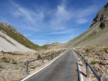 Empty road leading towards mountains against sky