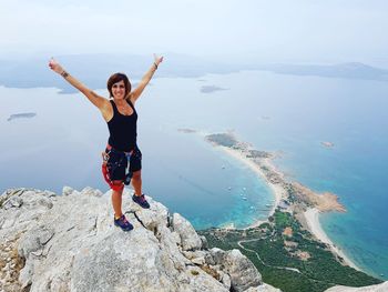 Portrait of happy woman standing on cliff by sea