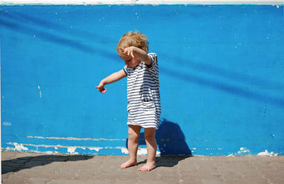 Full length of child standing against blue sea