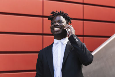 Full length of smiling man standing against wall