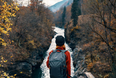 Rear view of person standing on rock during autumn