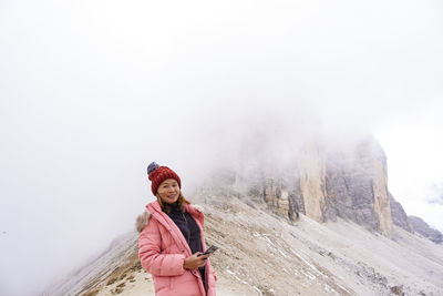 Portrait of woman standing against rock formation during foggy weather