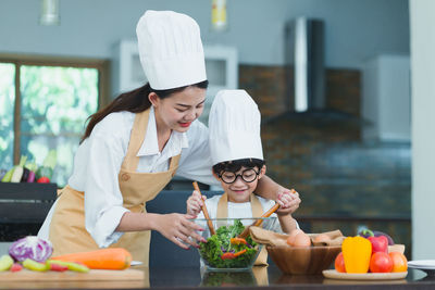 Woman holding food while standing in kitchen