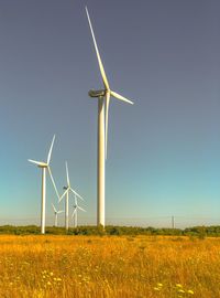 Windmills on field against clear sky