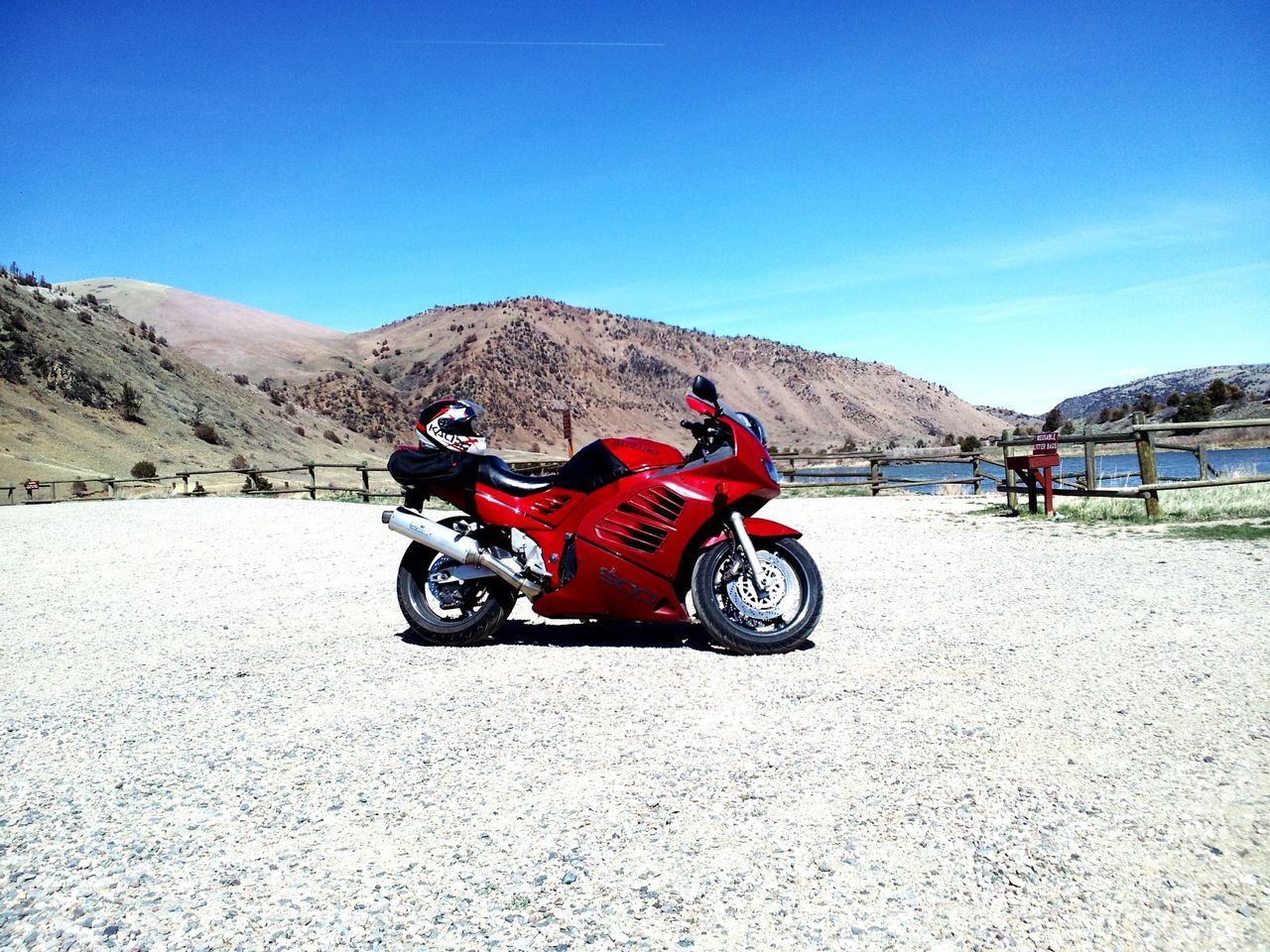 MAN RIDING MOTORCYCLE ON ROAD AGAINST MOUNTAINS