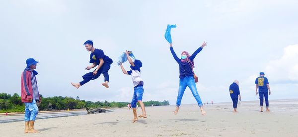 People enjoying at beach against sky