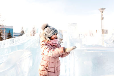 Cute smiling girl playing with ice while standing outdoors