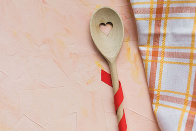 Stirring spoon and kitchen towel on pink background, copy space