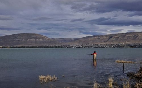 Man standing by lake against sky