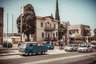 Cars on road by buildings against sky in city