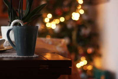 Close-up of mug on table against defocused christmas lights