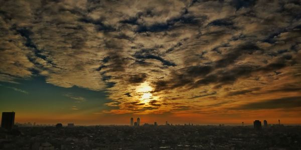 Silhouette cityscape against sky during sunset