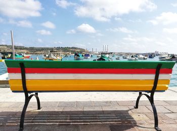 Deck chairs on shore against sky