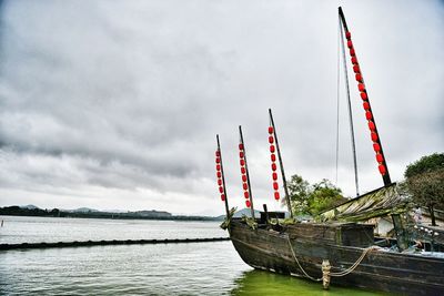 Lone boat in calm sea against cloudy sky