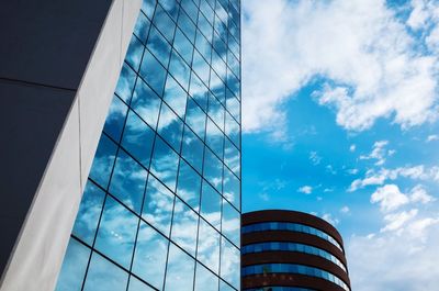 Low angle view of glass building against cloudy sky