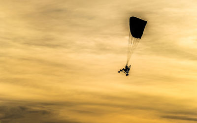 Low angle view of person paragliding against sky