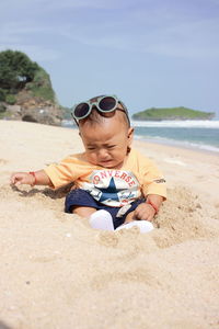 Low section of woman wearing sunglasses on sand at beach