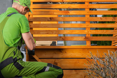 Rear view of man standing on wooden wall