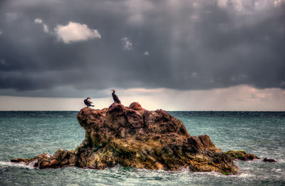 Rock formation on beach against sky