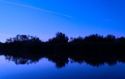 Reflection of trees in lake against blue sky