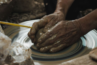 Cropped hands of person molding shape on pottery wheel
