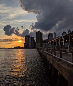 Scenic view of sea by buildings against sky during sunset