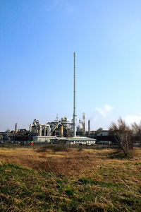 Factory on field against clear blue sky