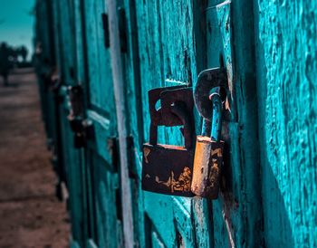 Close-up of rusty padlocks on turquoise doors