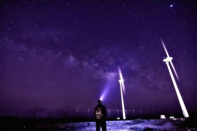 Man with flashlight standing against star field on field