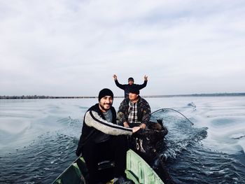 Portrait of happy friends on boat sailing in sea against sky